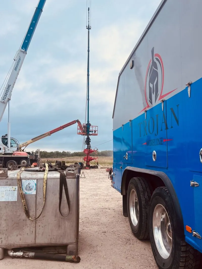 A Trojan wireline unit rigged up next to a crane and wellhead on a South Texas lease.